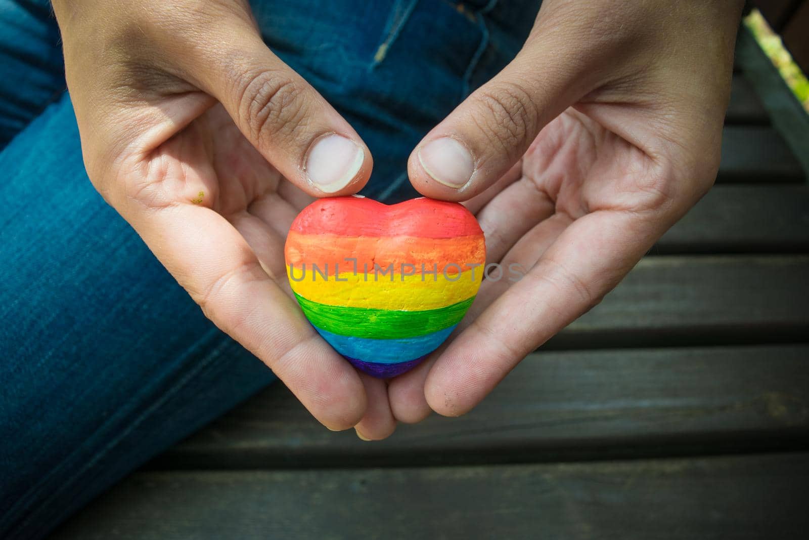 Heart with rainbow stripes in female hands. LGBT pride flag, symbol of lesbian, gay, bisexual, transgender for social movements. Homosexual love,Equality or Human rights concept. Copy space.