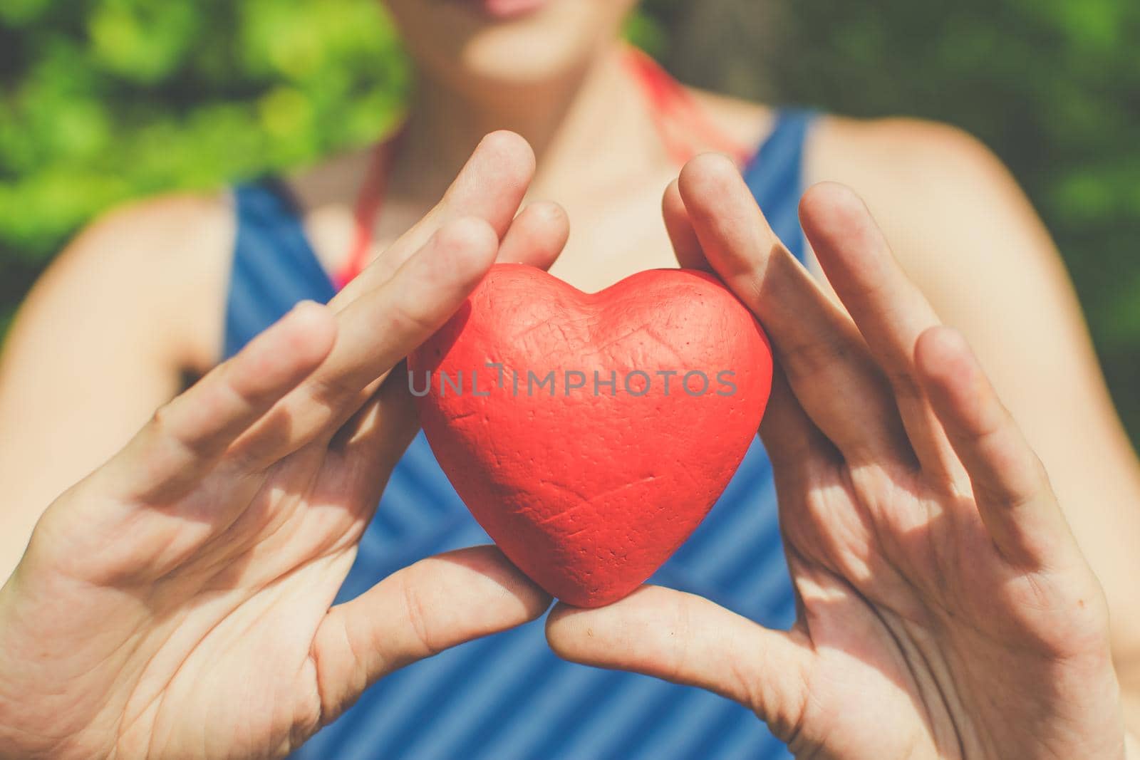 people, relationship and love concept - womans hands holding red heart on blue background