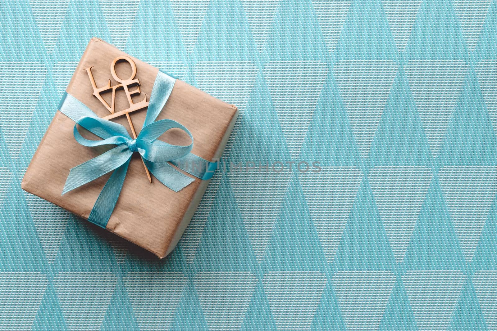 Gift box with blue ribbon on blue background. Freespace