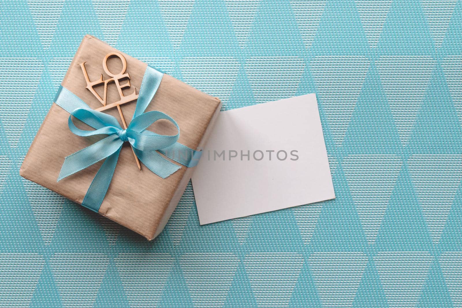 Gift box with blue ribbon on blue background. Freespace