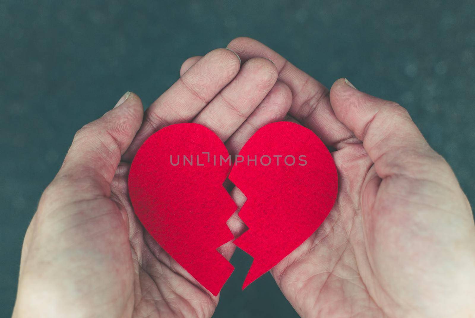 Broken red heart in the hands - divorce concept