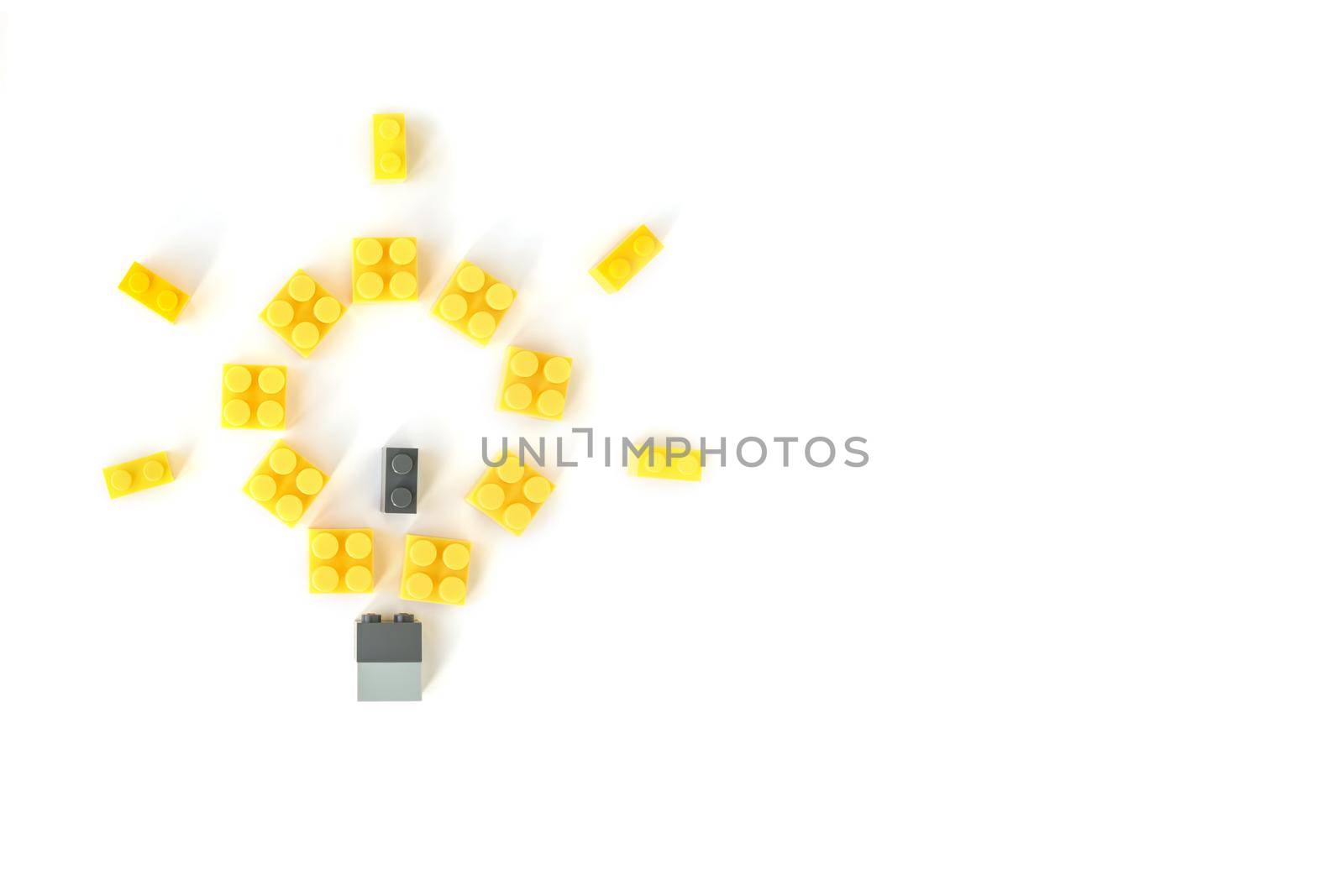 Idea concept. Lamp made of yellow plastic constructor bricks on white background. Popular toys.