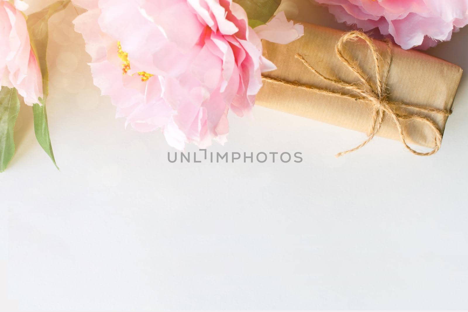 Bouquet of flowers and gift box wrapped with craft paper on white background with copy space for text. Greeting concept. Flat lay. Top view