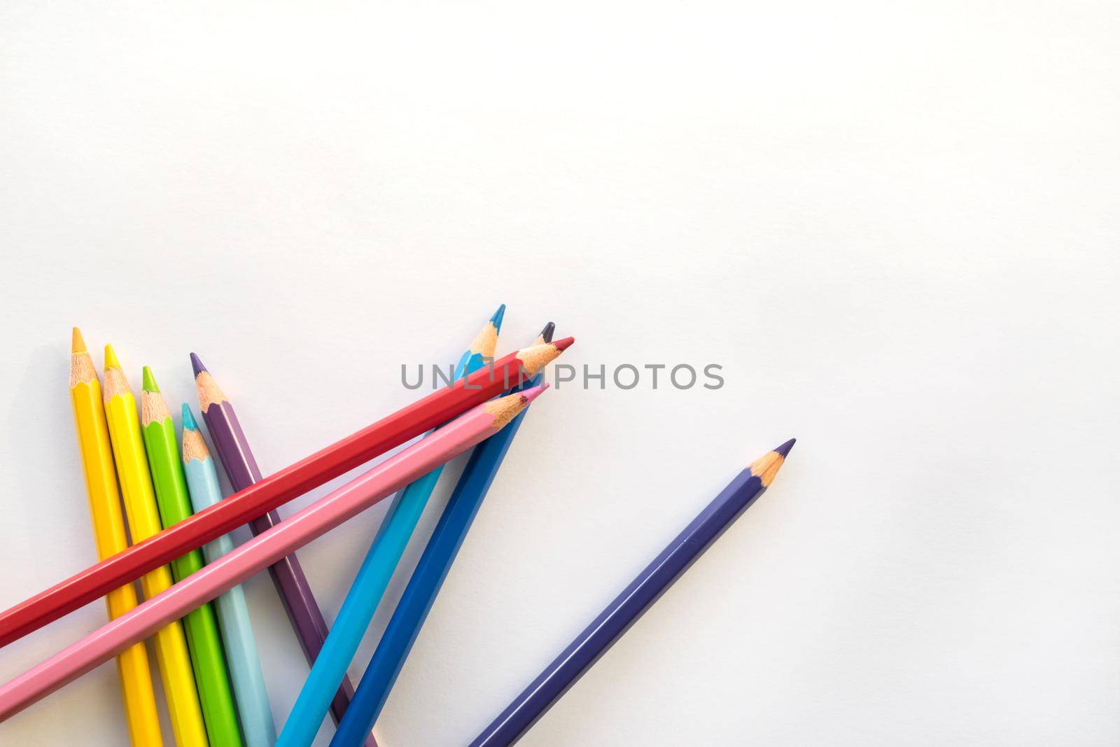 Color pencils on white paper background, copy space. Office supplies, back to school. Top view.