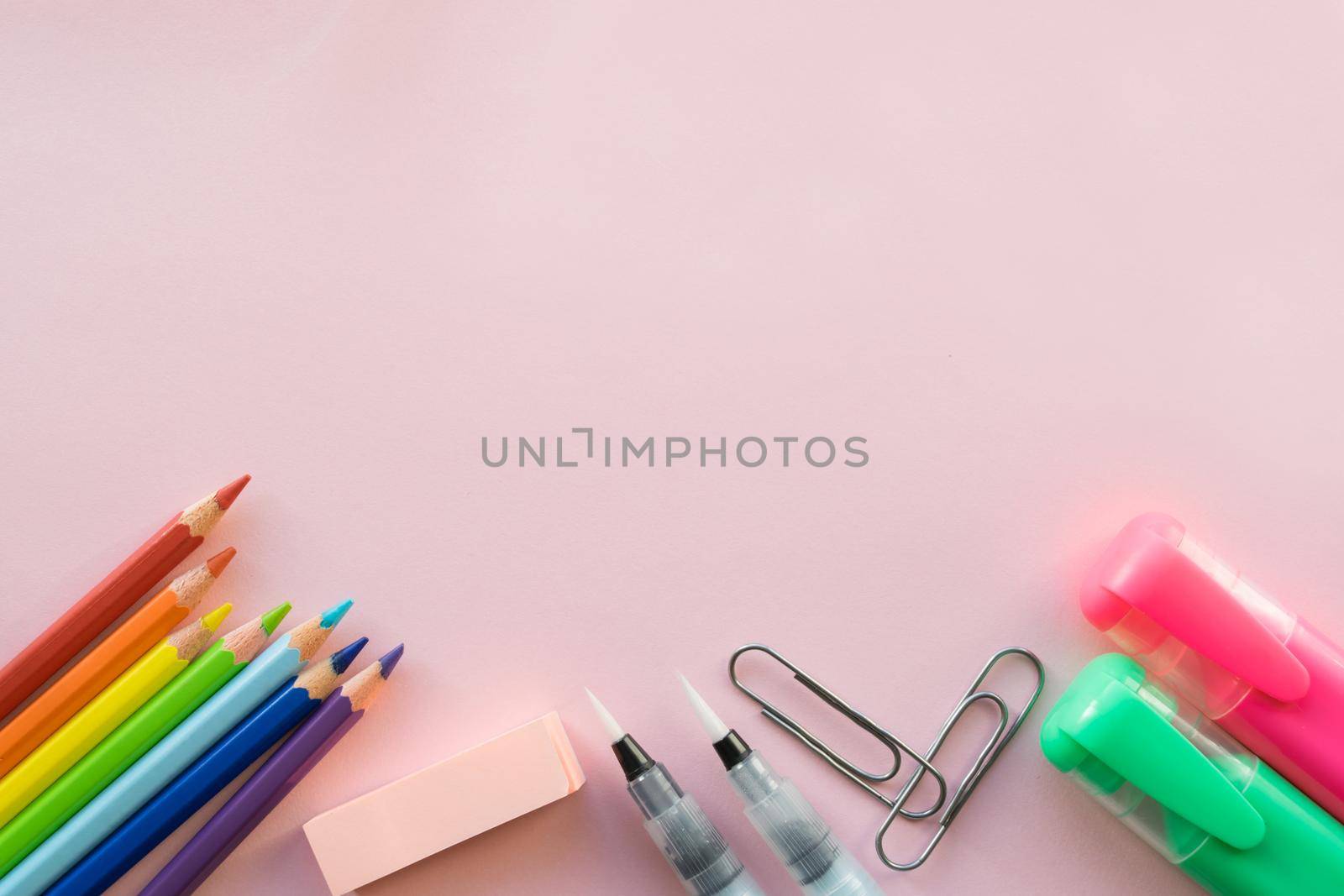 School and Office drawing supplies on pink background. Free space for text. Back to school. Top view border of colour pencils, marker and brushes