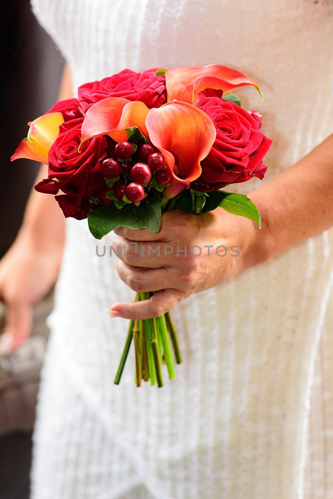 bride wearing a modern wedding bouquet of roses against a white wedding dress
