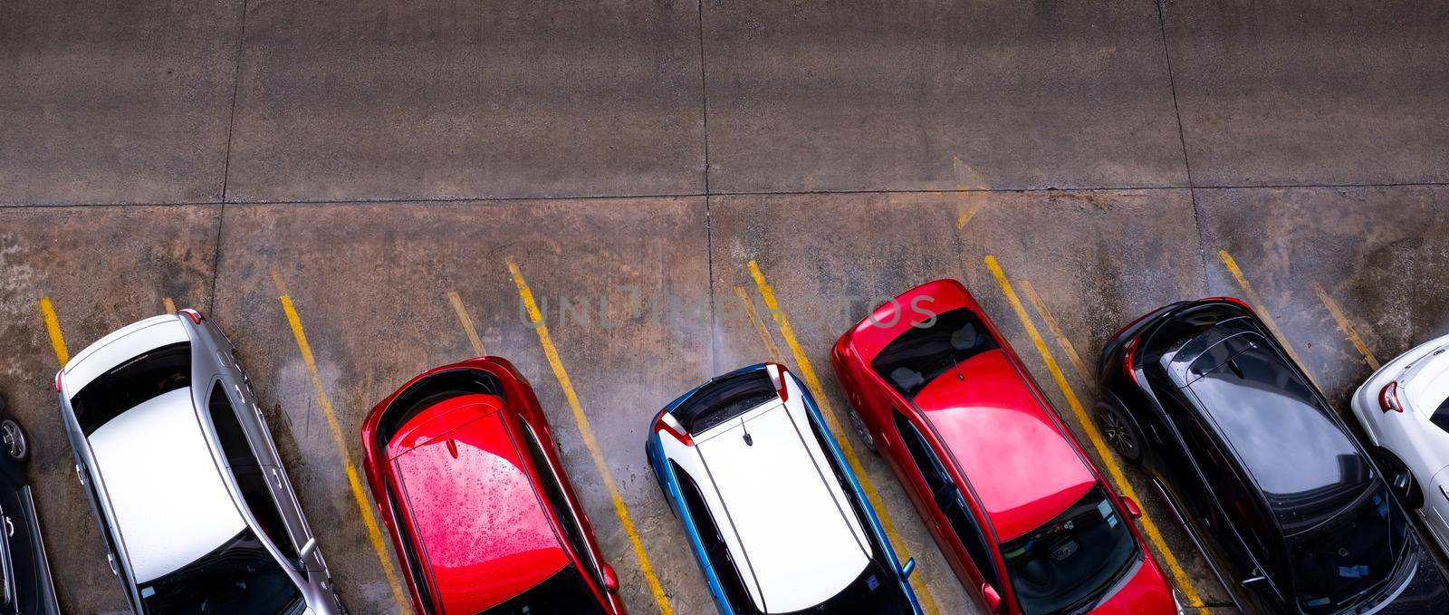 Top view of car parked at concrete car parking lot with yellow line of traffic sign on the street. Above view of car in a row at parking space. No available parking slot. Outside car parking area. by Fahroni