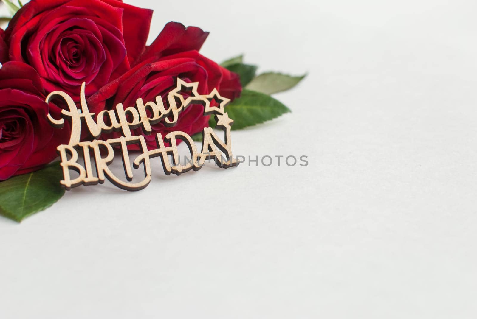 Composition of bouquet of red roses and decorative wooden greeting on white background. Happy Birthday. Space for text. Copyspace