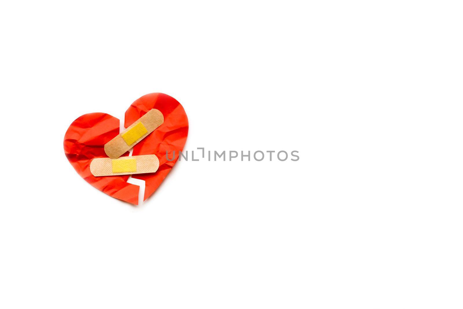 Broken red heart symbol with medical patch on white background, love concept. healing. Copyspace