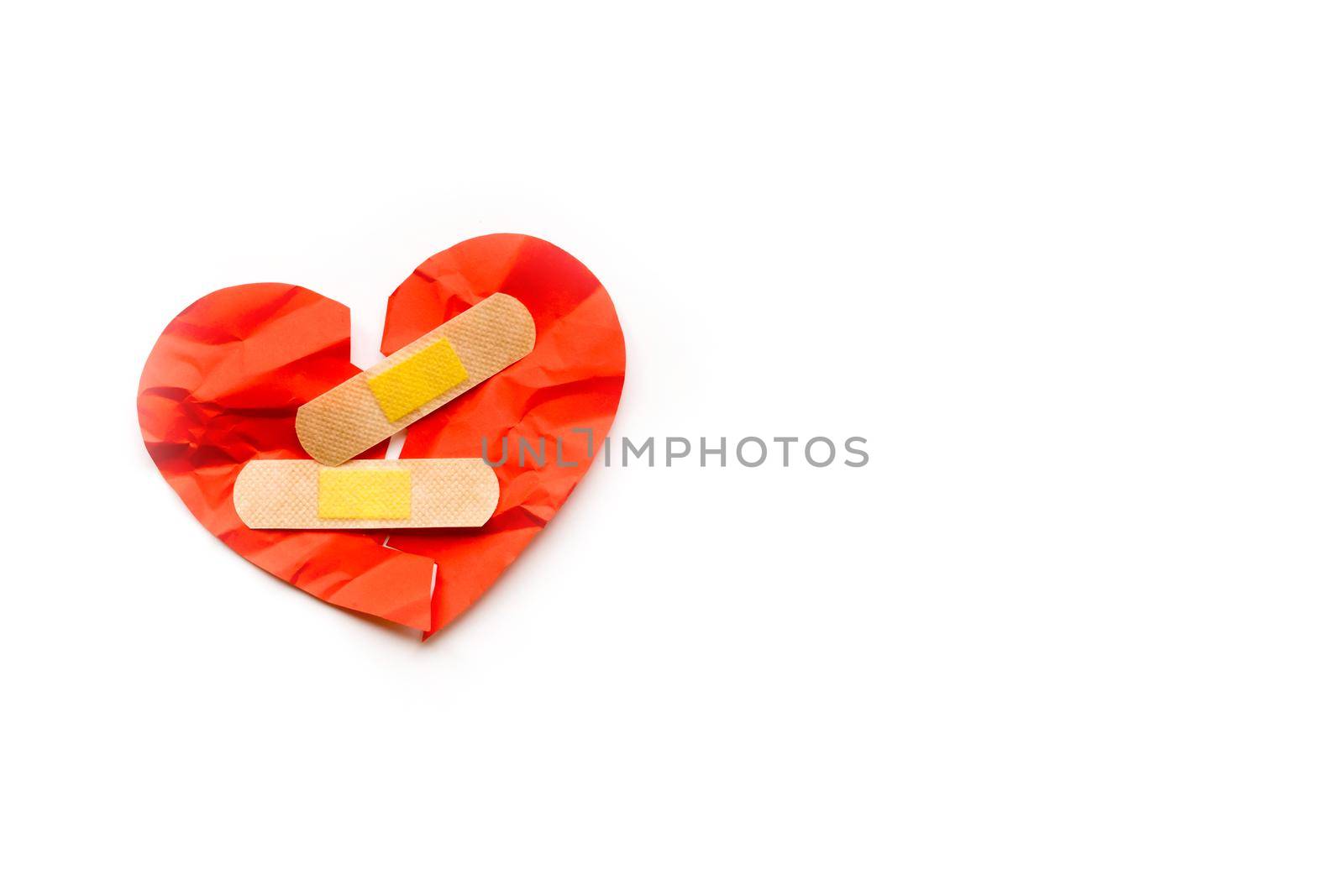 Broken red heart symbol with medical patch on white background, love concept. healing. Copyspace