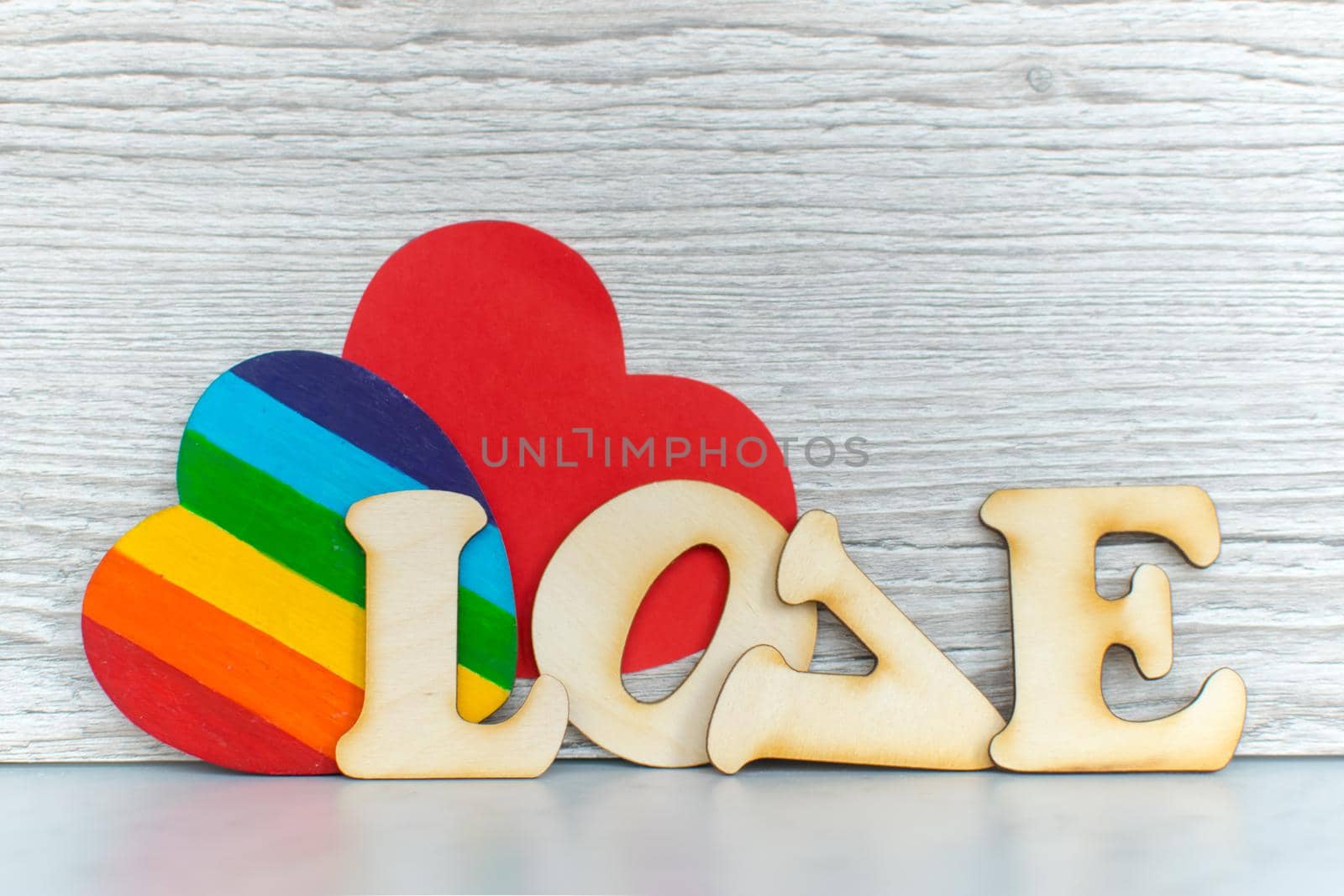 Valentines Day card background, Rainbow cute heart like a LGBT pride rainbow flag with red paper heart and decorative wooden word. Valentine Day romantic. Love human rights and freedom concept. Copyspace
