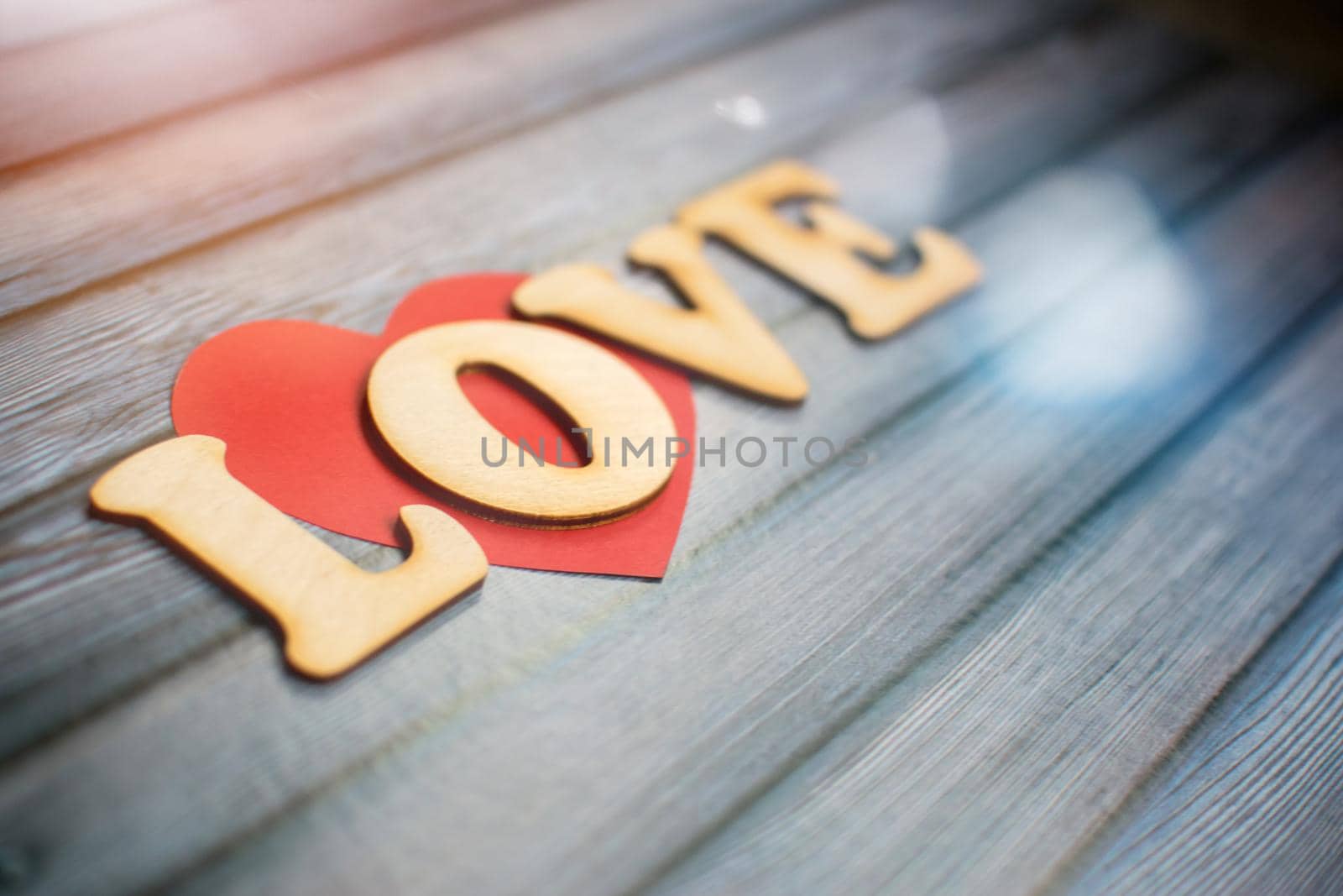Valentines Day card background, red cute heart made of paper with decorative wooden word on blue background. Valentine Day. Love concept. Selective focus. Copyspace