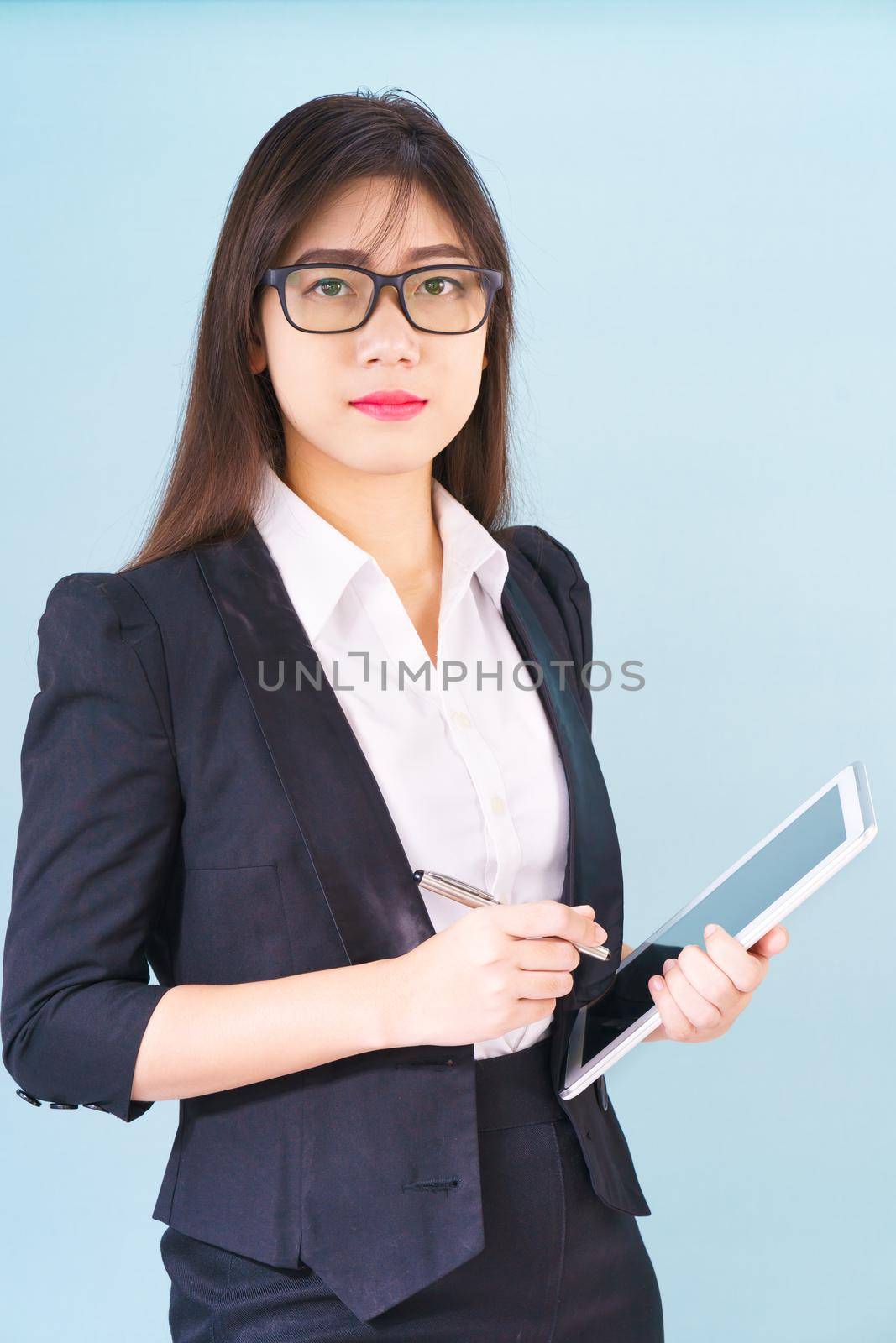 Young Asain women in suit standing using her digital tablet against blue background