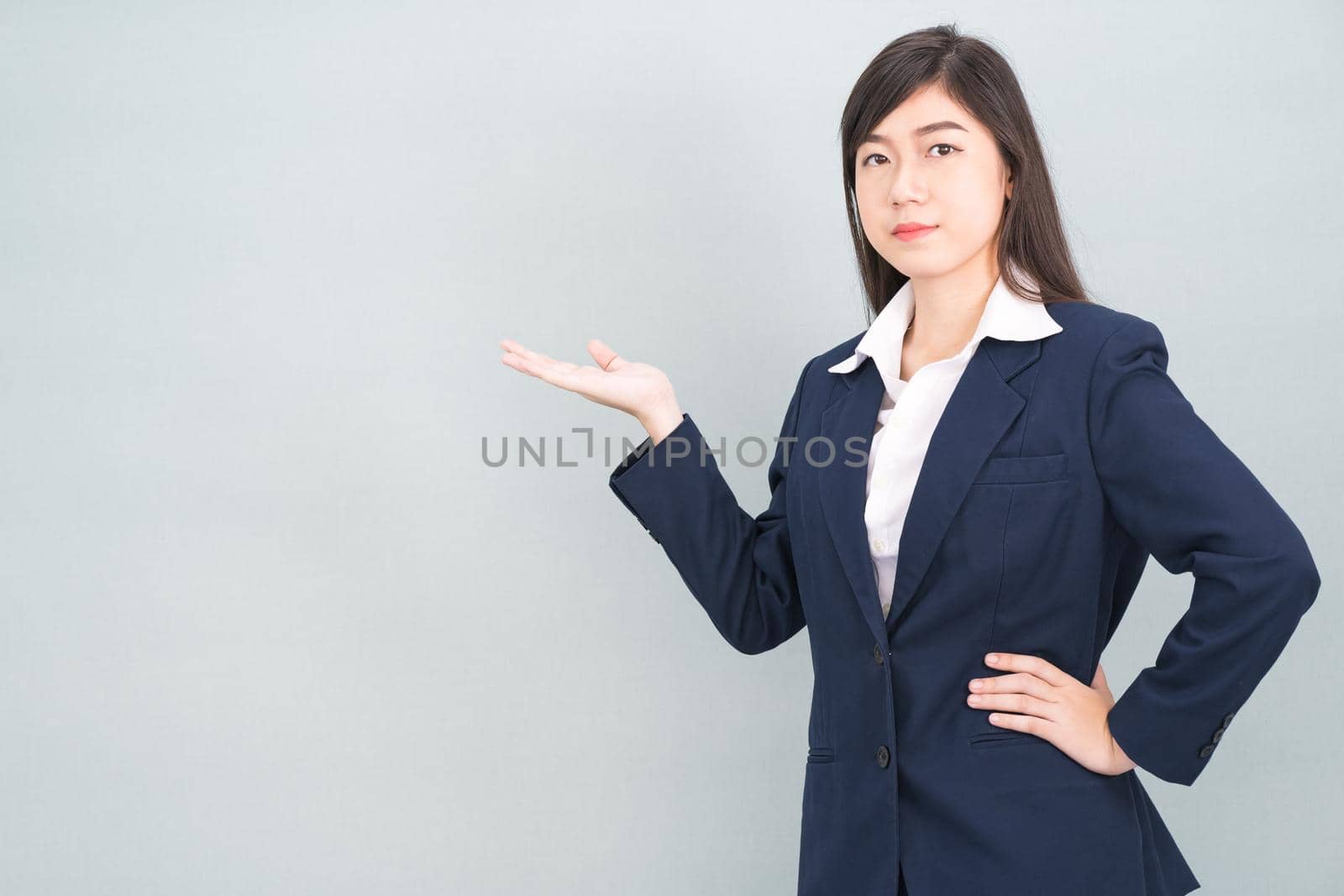 Asian woman in suit open hand palm gestures with empty space isolated on gray background