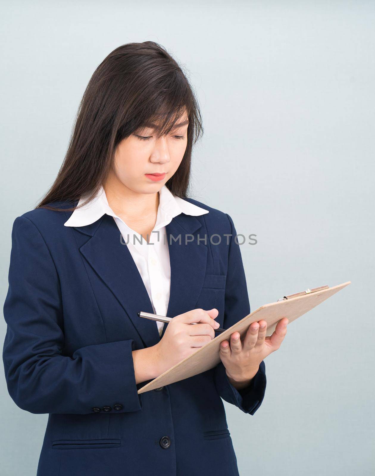 Portrait of Asian woman long hair and wearing suit  with clipboard and pen in hands thinking about success, isolated on white background