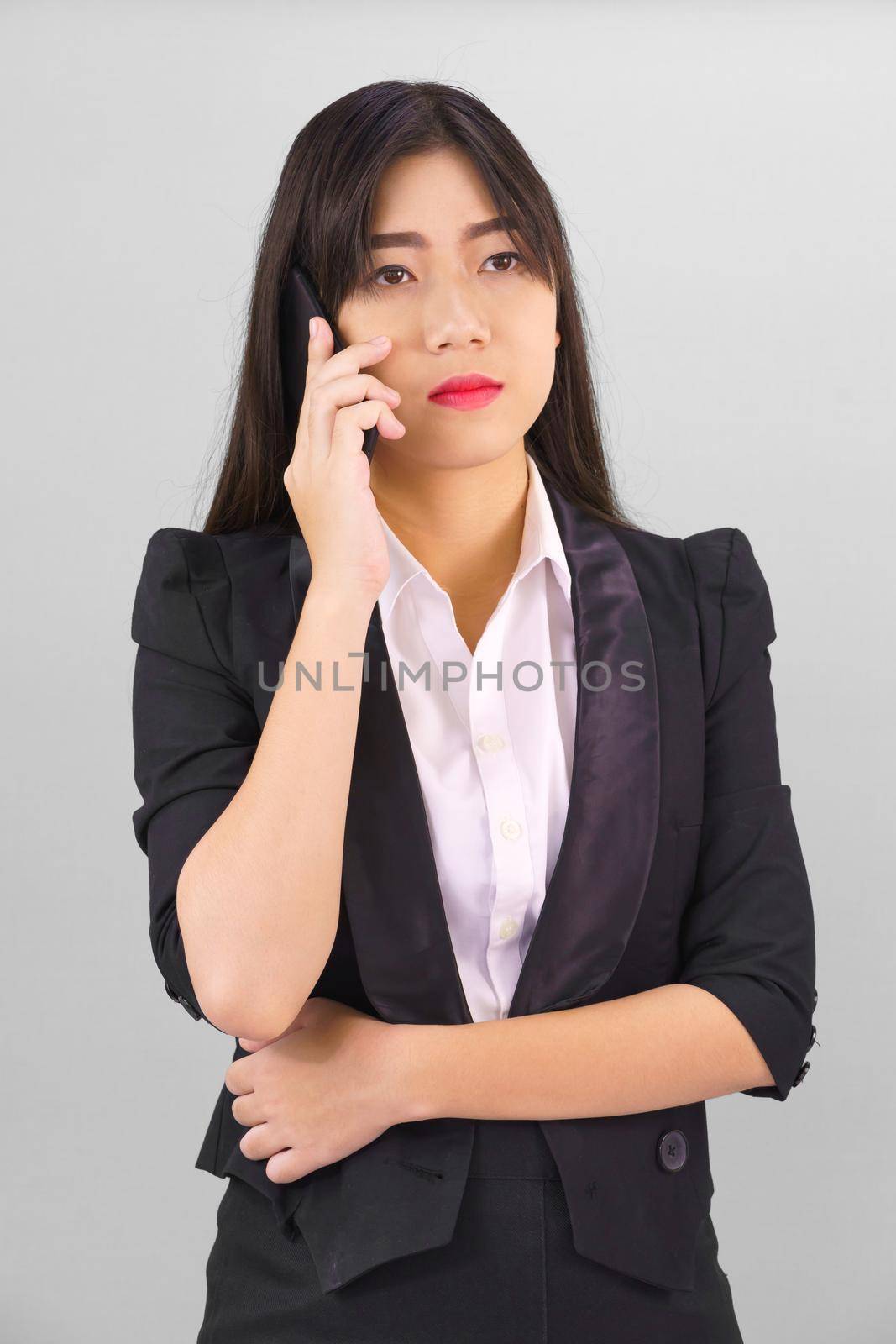 Young Asian women in suit standing posing using her phone against gray background