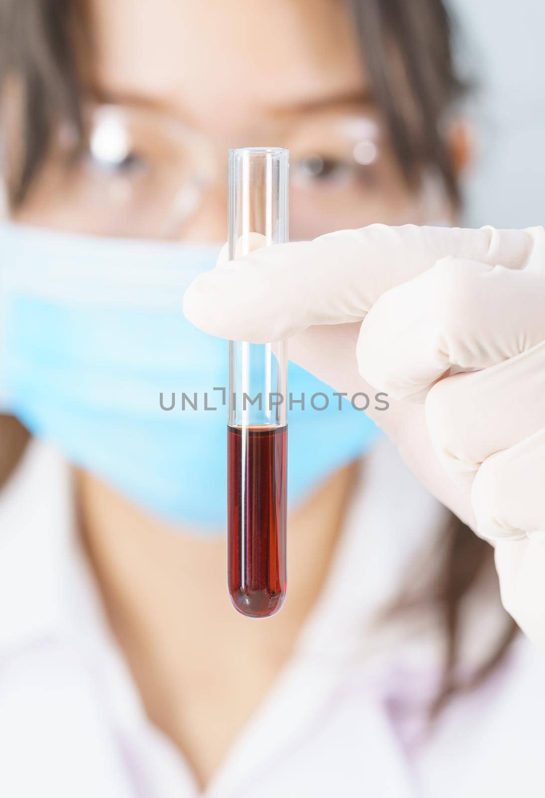 Scientist analyzing holding blood sample in test tube by stoonn