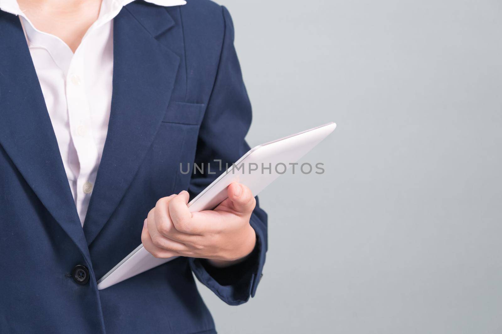 Woman in suit using computer digital tablet isolated on gray background