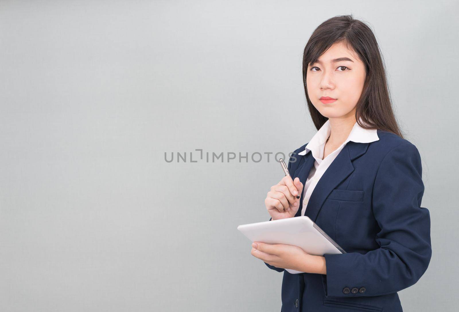 Woman in suit using computer digital tablet isolate on gray background