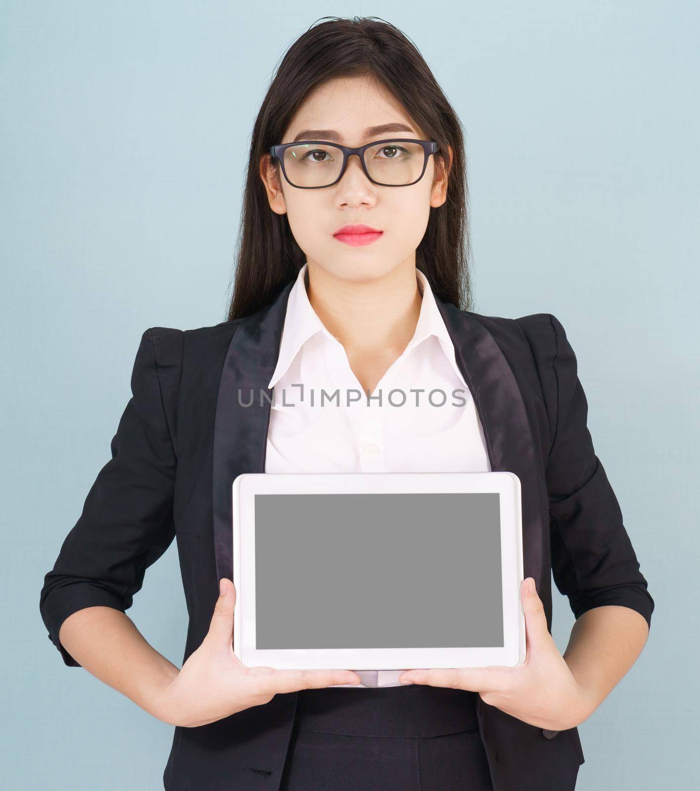 Young asian women in suit holding her digital tablet standing against green background