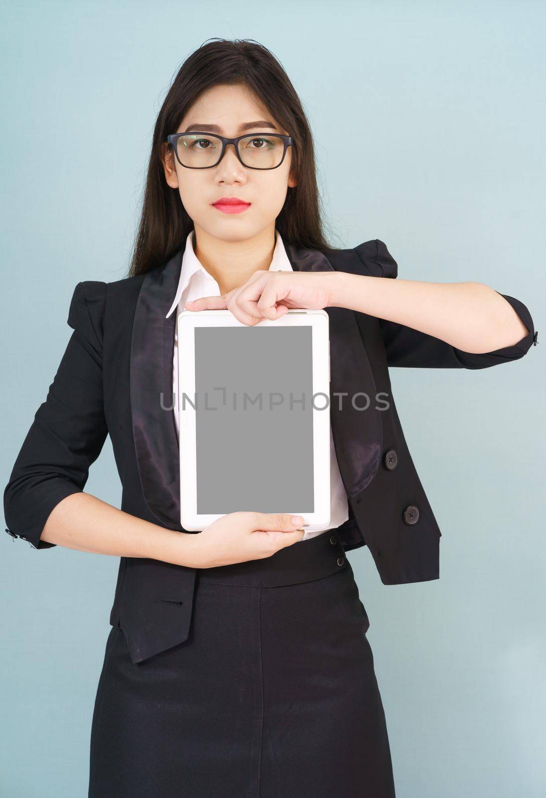 Young asian women in suit holding her digital tablet standing against green background