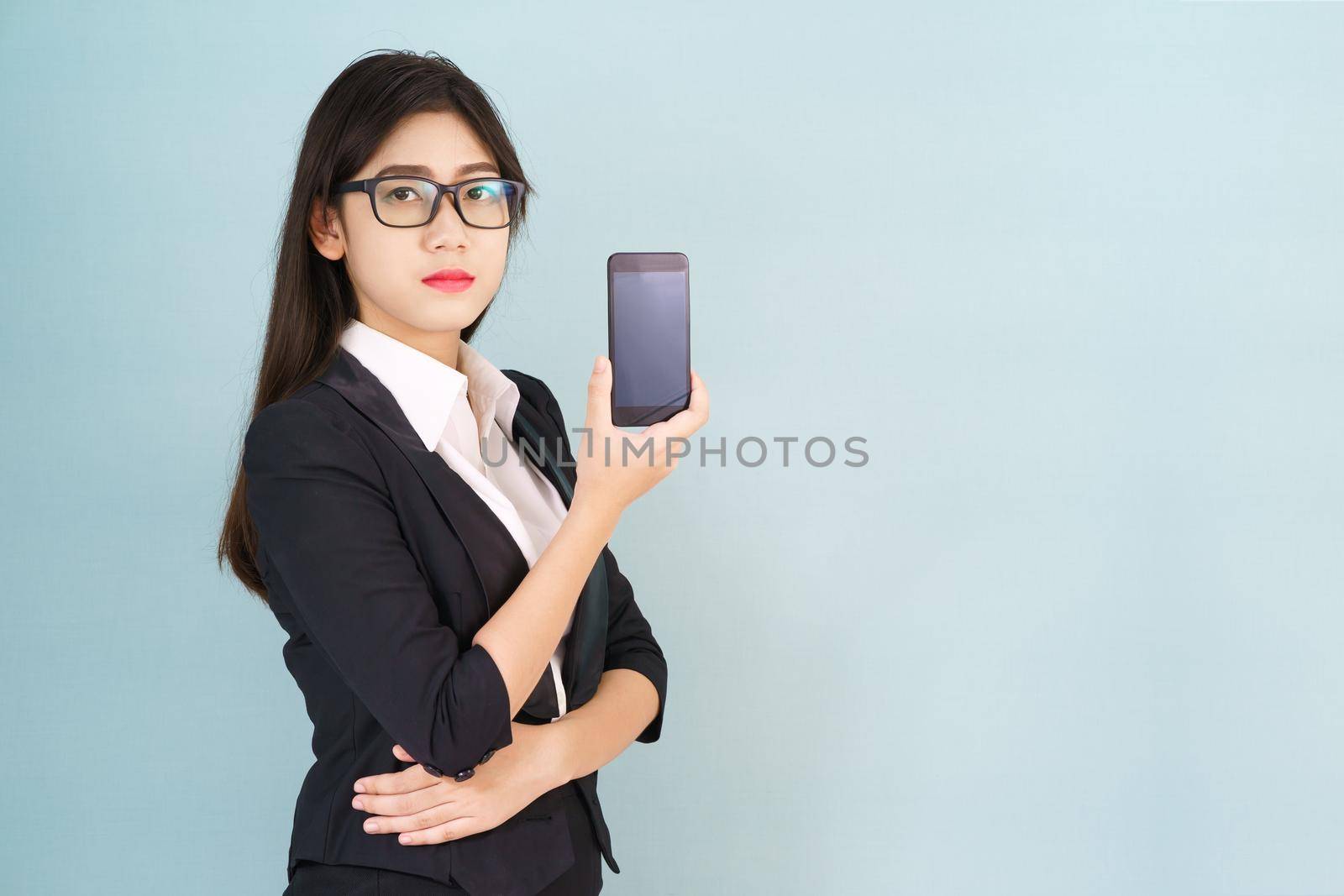 Young women in suit holding her smartphone standing against blue background