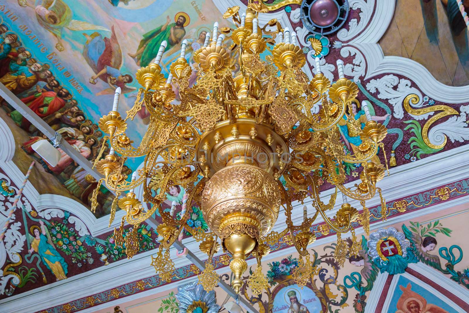 Church of Elijah the Prophet in Yaroslavl 11.07.2019. gilded hanging chandelier on the background of the walls with paintings. The lamps are made in the form of candles.