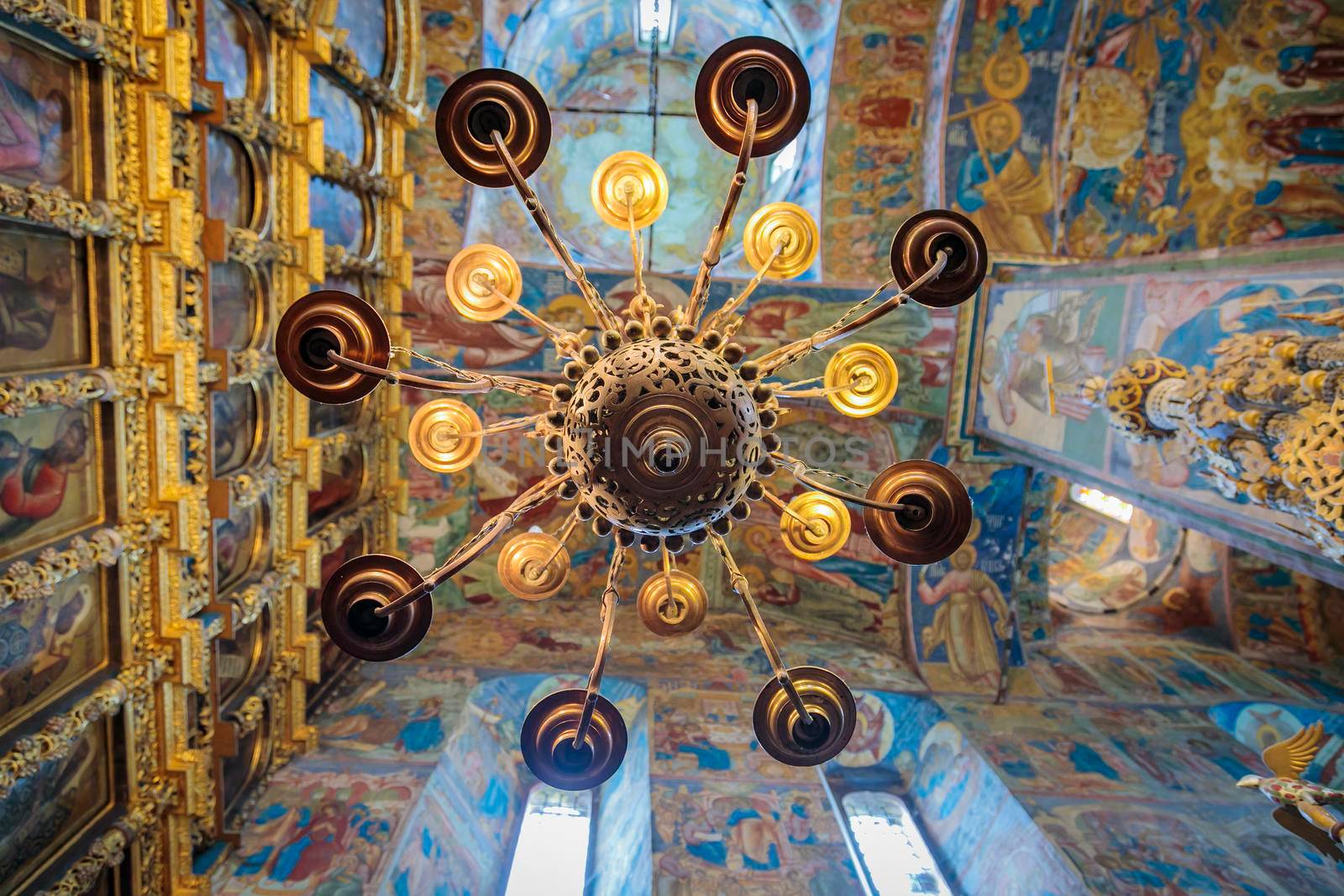 Church of Elijah the Prophet in Yaroslavl 11.07.2019. a high-hanging chandelier on the background of walls with painted icons of saints.