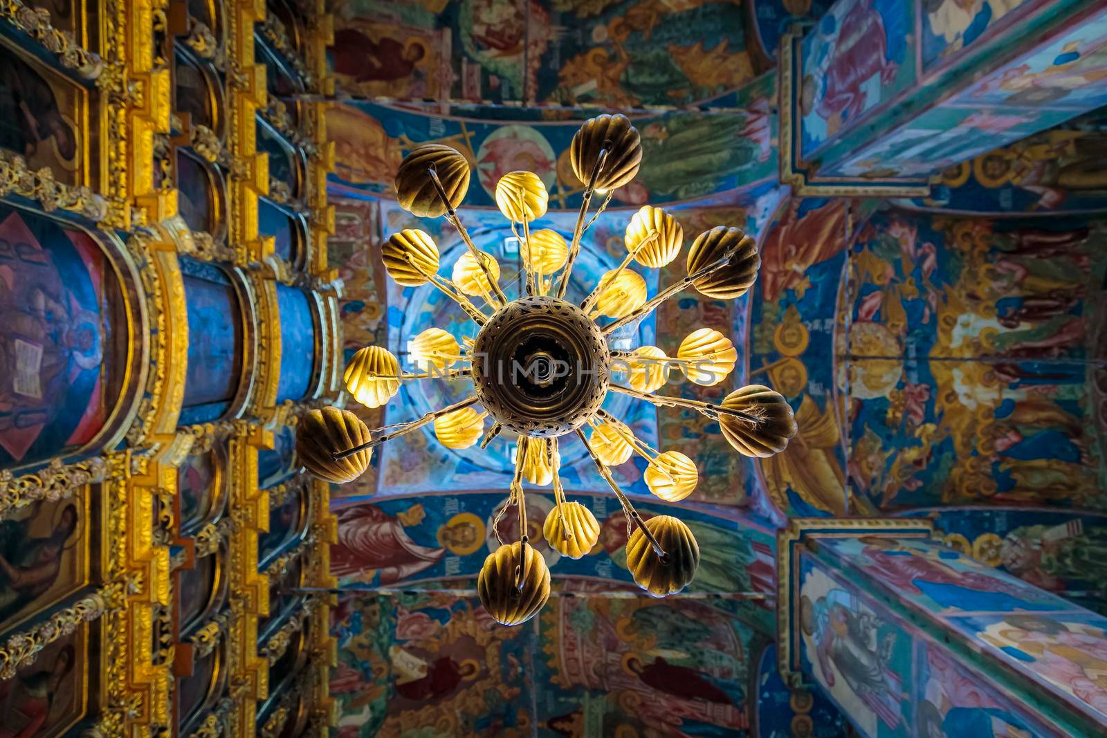 Church of Elijah the Prophet in Yaroslavl 11.07.2019. a high-hanging chandelier on the background of walls with painted icons of saints.