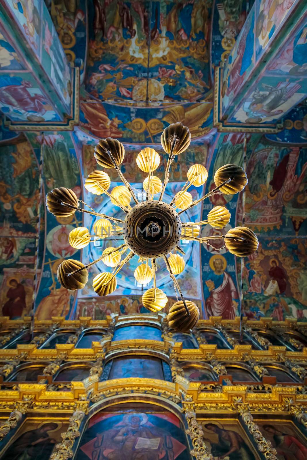 Church of Elijah the Prophet in Yaroslavl 11.07.2019. a high-hanging chandelier on the background of walls with painted icons of saints.