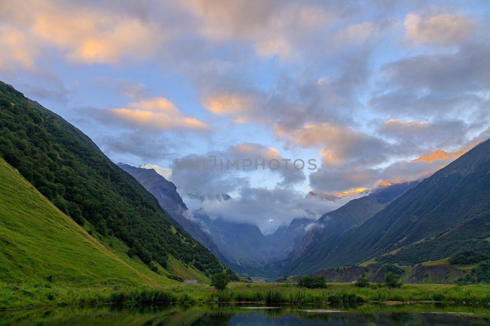 High mountains of the Caucasus with a beautiful view. Green vegetation and shrubs on sharp rocks, between the mountains of the lake. Magnificent mesmerizing landscape.