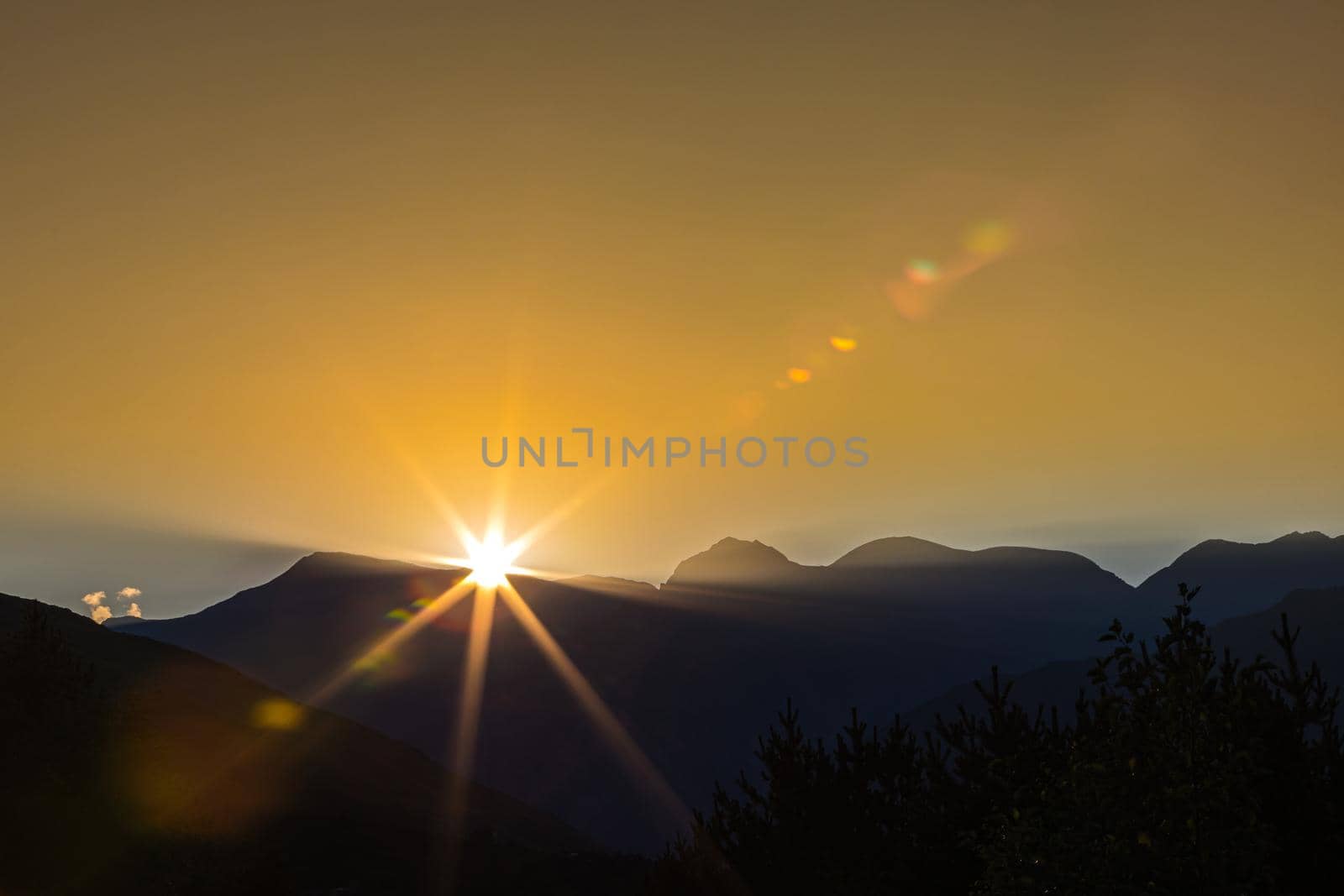 Early morning in the mountains, the first rays of the sun come out over the peaks of the ridge. Magnificent mesmerizing landscape.