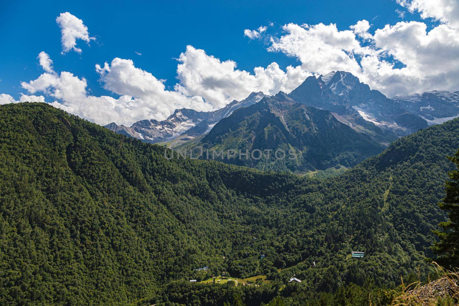 High mountains of the Caucasus with beautiful views. Green vegetation and dense forest above a blue sky. A great fascinating landscape.