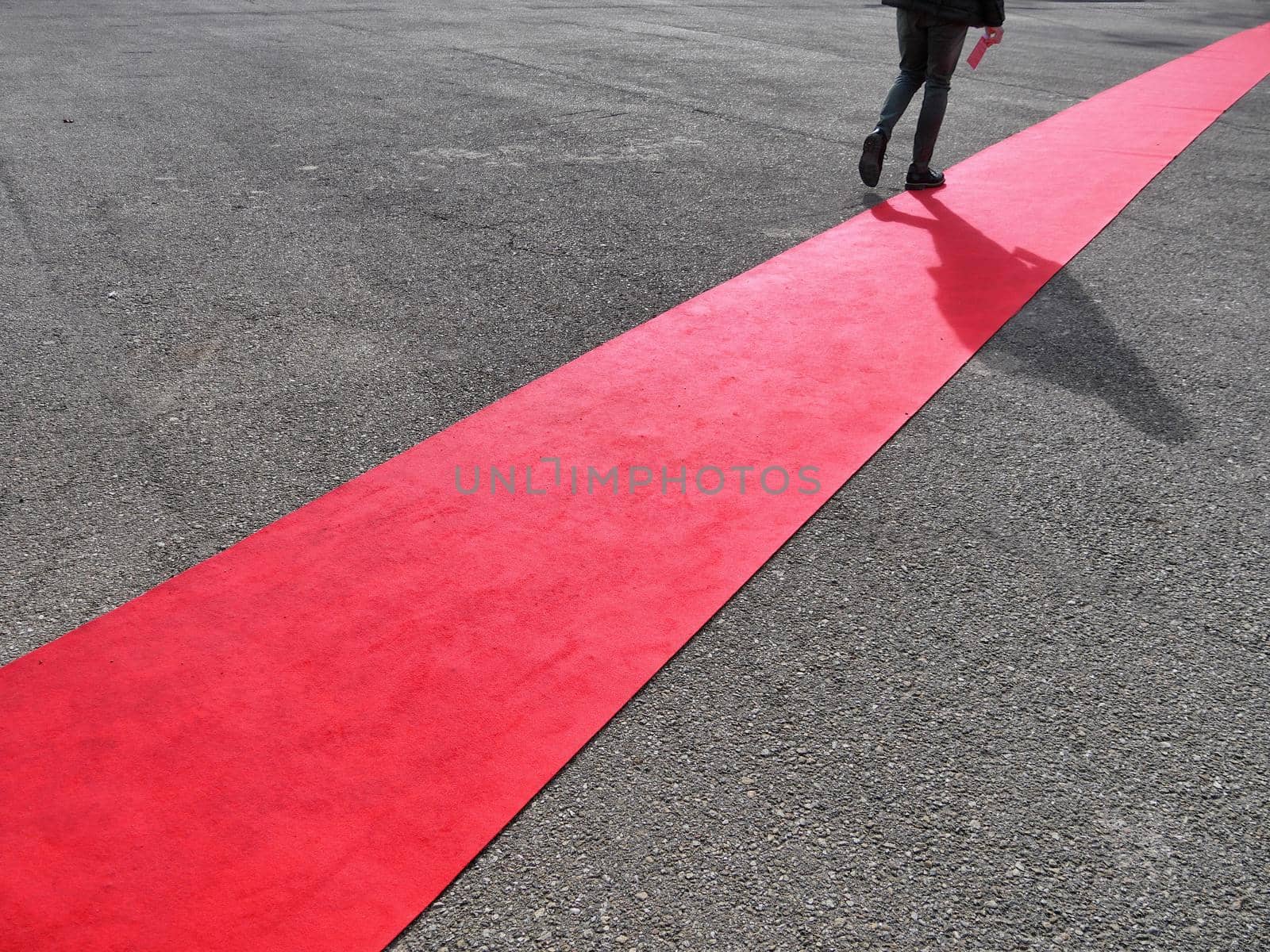 Walking persons and own shadows on red carpet close view on legs