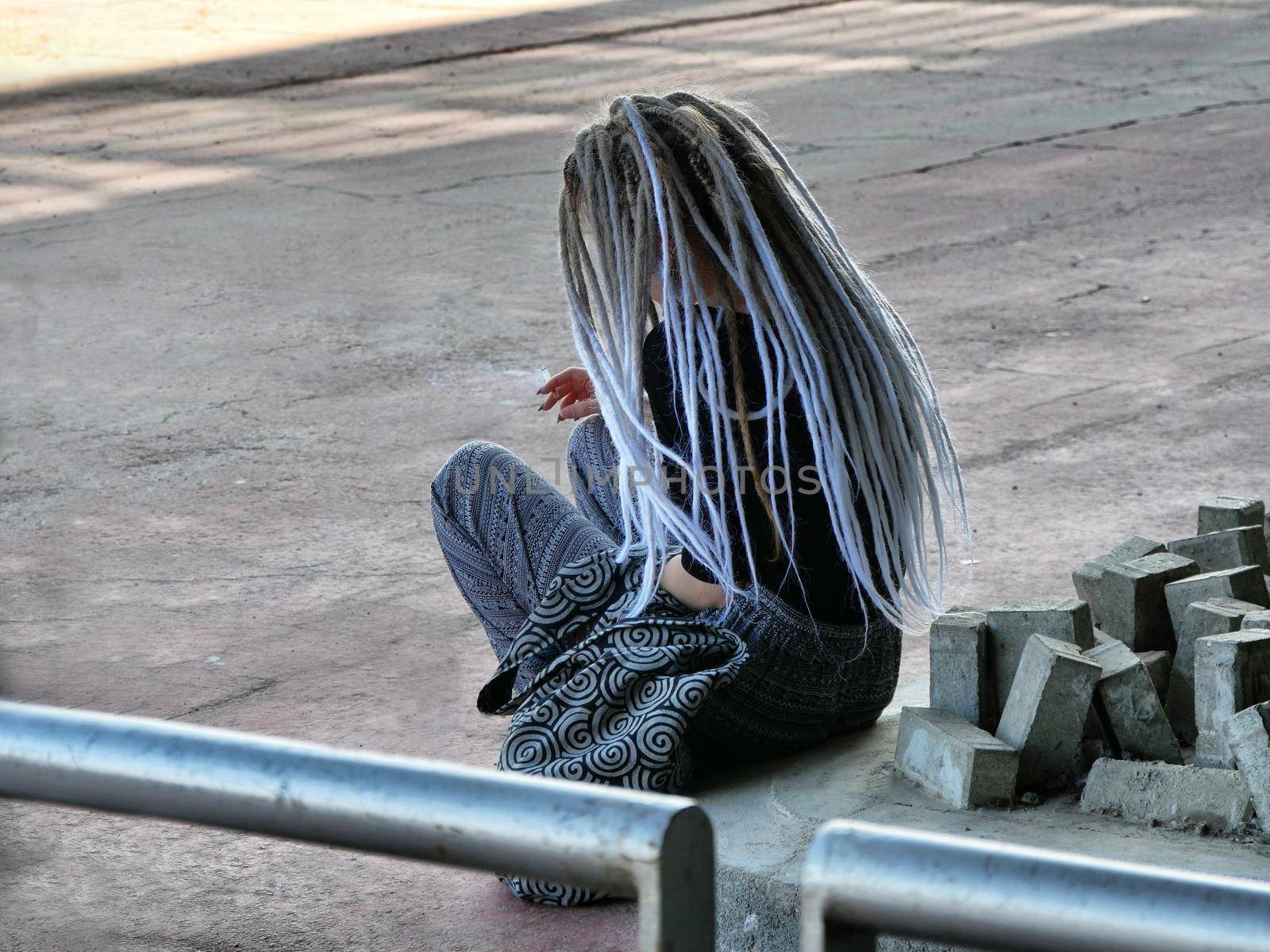 Long color gradient dreadlocks haired girl seated view from behind