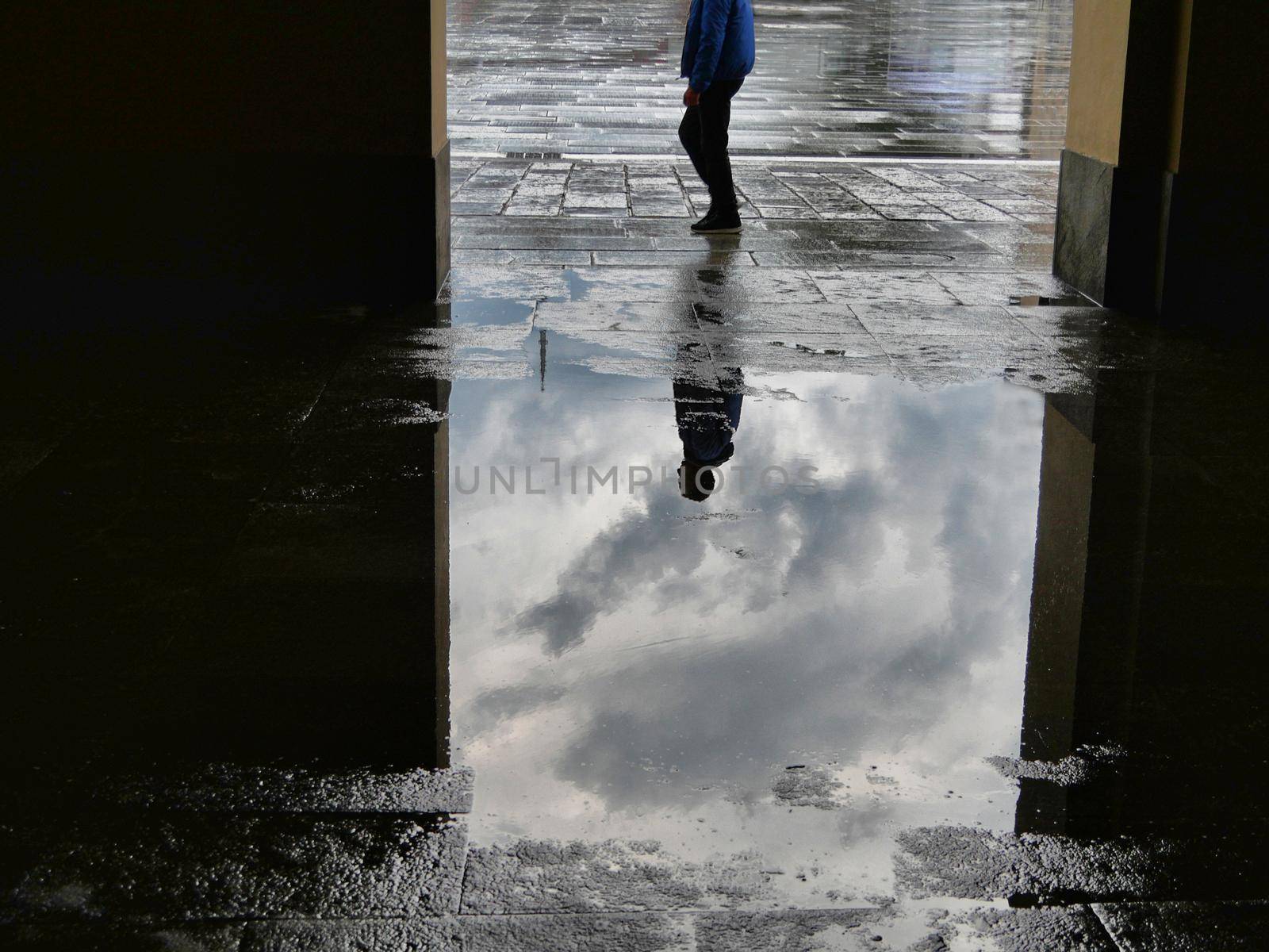 People silhouettes reflected in puddle of water after the storm by lemar