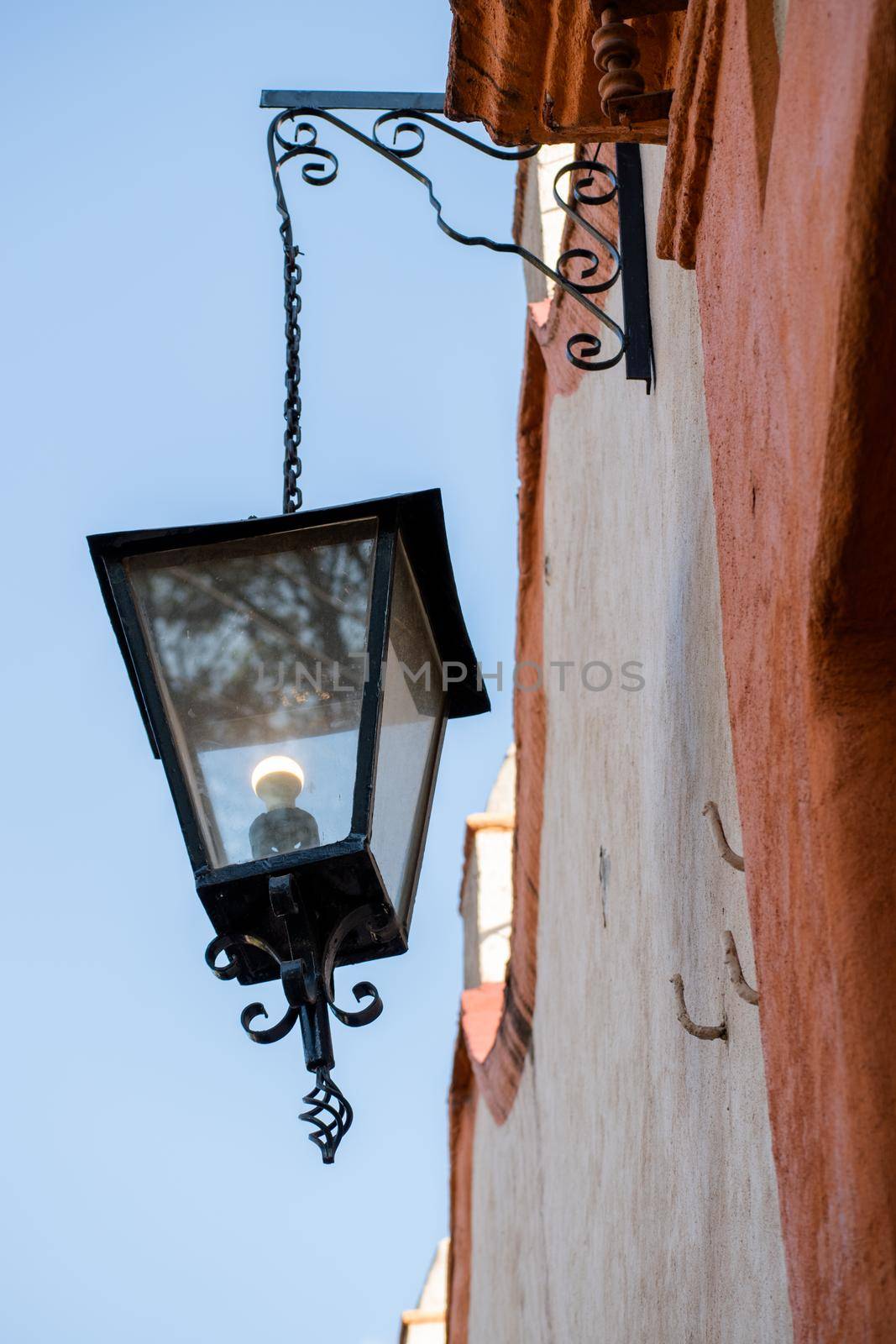 Classic lantern hanging from old building under a blue sky by Kanelbulle