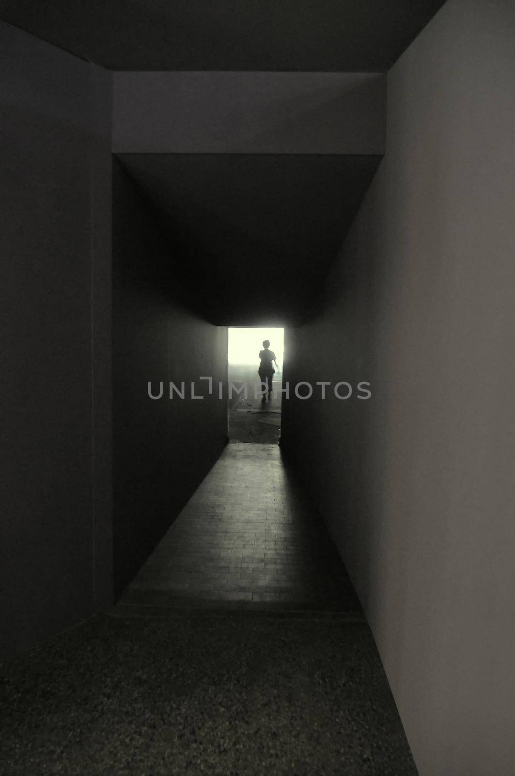 Iconic black and white picture of dark narrow corridor with individual silhouette escaping to light