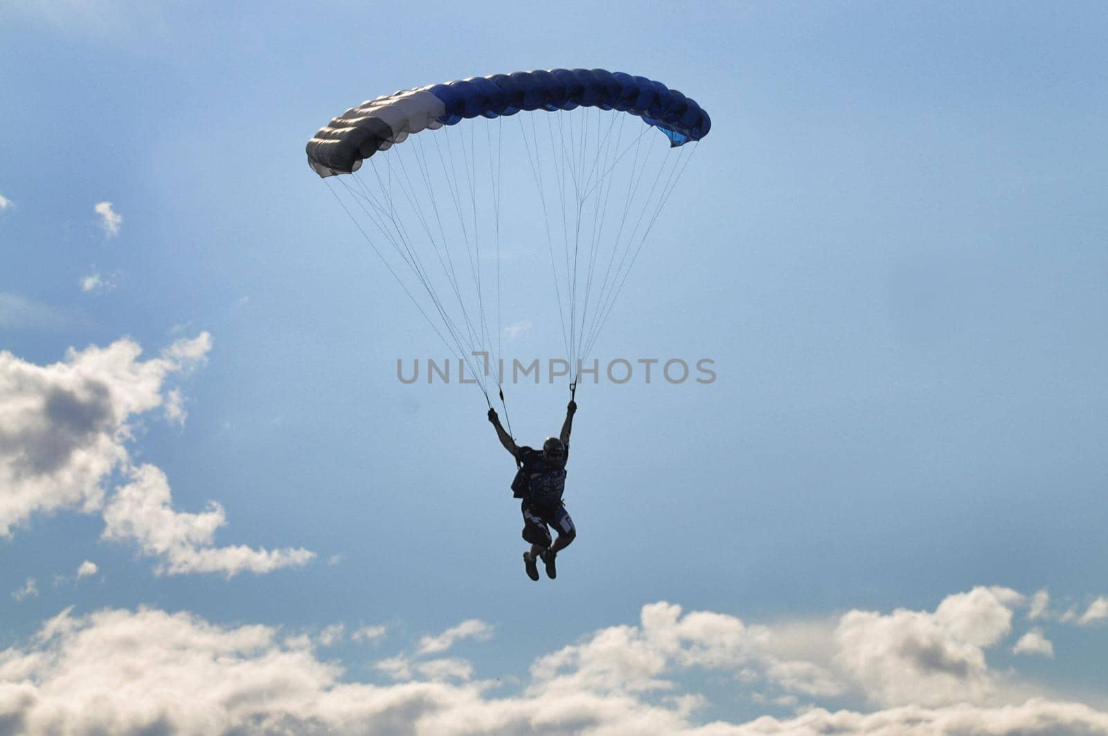 Parachutist silhuette on blue cloudy sky by lemar