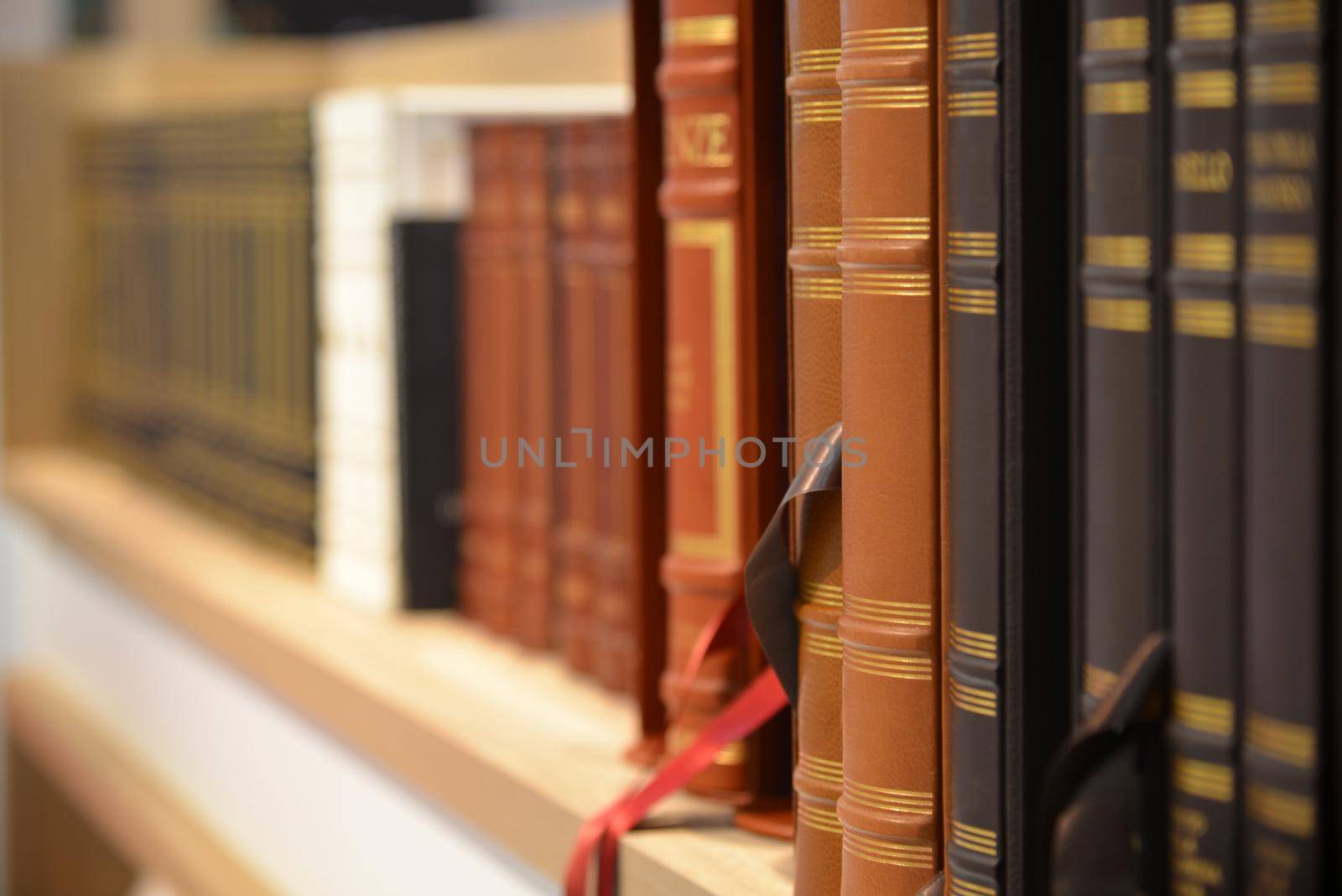Bookshelf in perspective view with row of classical leather hardcover books by lemar