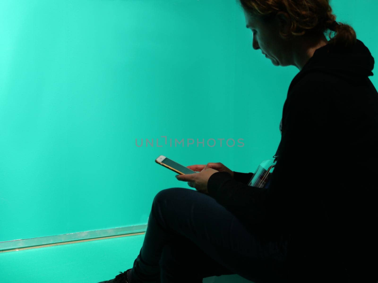 Lonely woman silhouette watching her smartphone isolated on blank green background