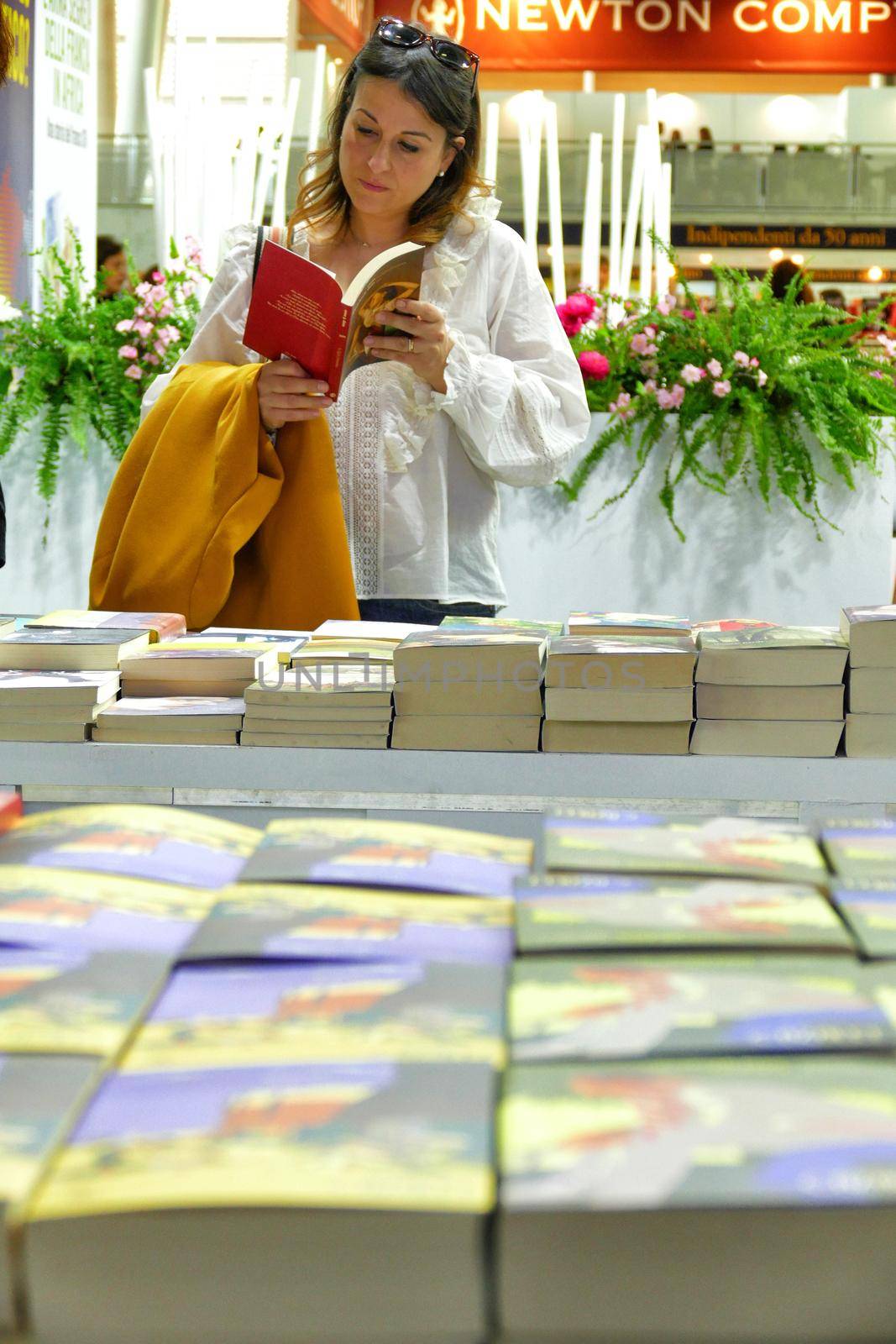 Woman reading and picking books in library store of international book fair Turin Italy May 10 2019 by lemar