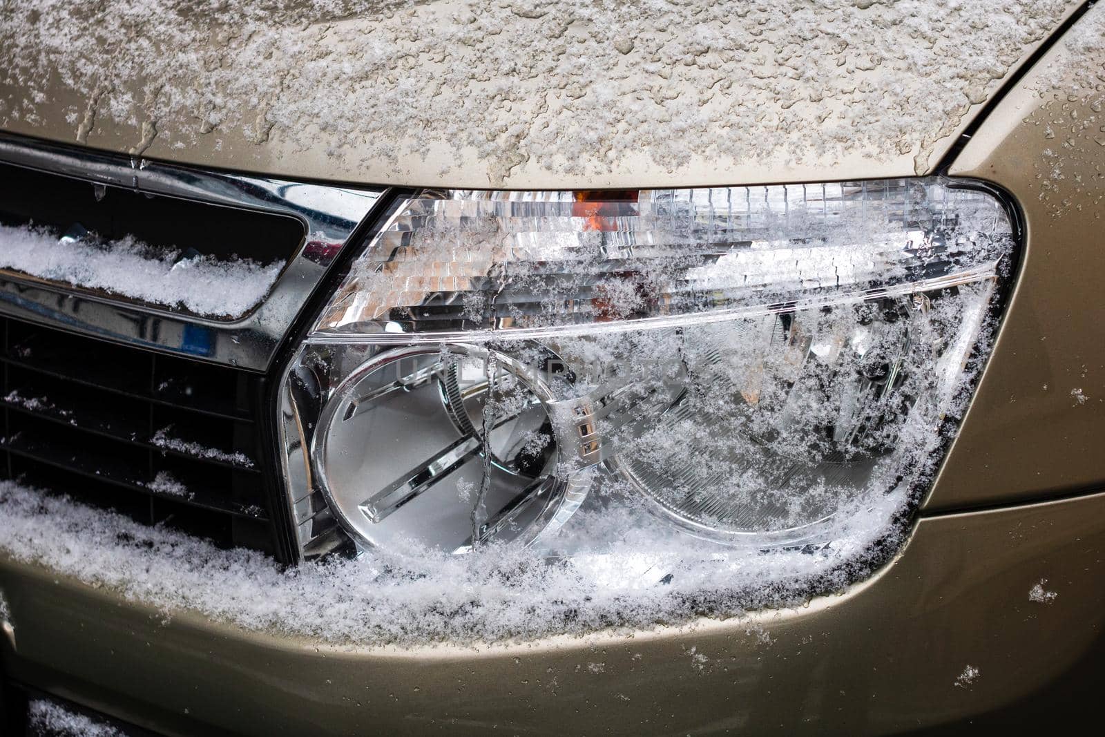 Car headlights covered with snow close up.