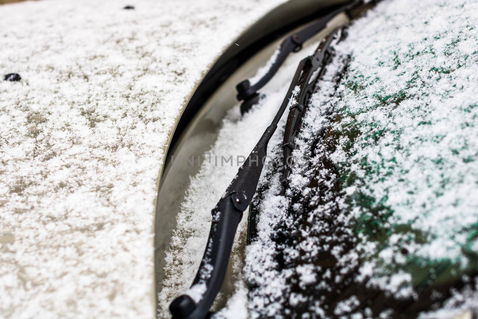 Snow on car, windshield wipers with snow close up.