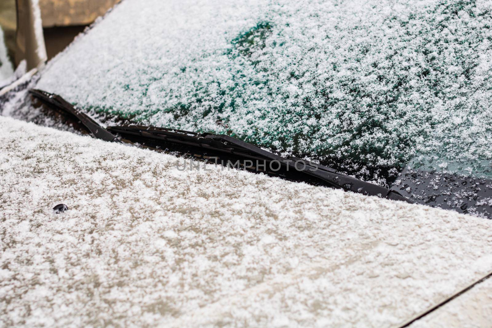 Snow on car, windshield wipers with snow close up.