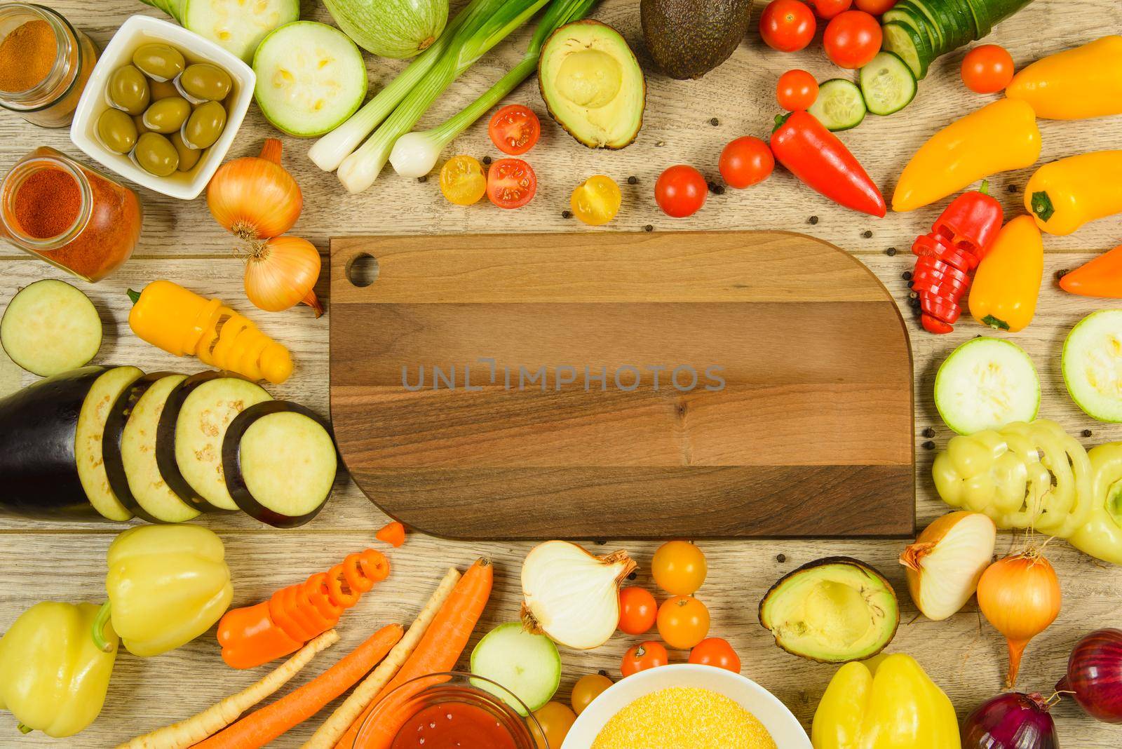 Flat lay view of chopping board frame of vegetables with fresh ingredients for healthy cooking on wooden table with copy space