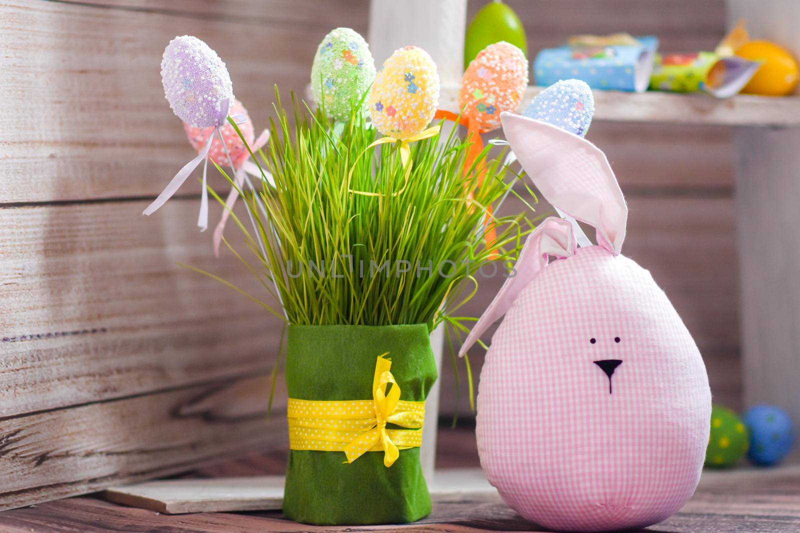 Easter composition. Funny creature, Easter eggs, green grass on a wooden background. High quality photo