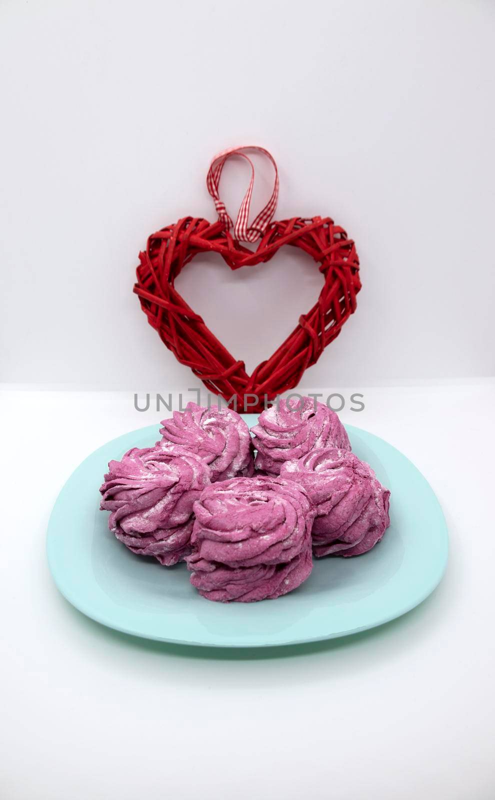 On a turquoise saucer, raspberry marshmallows for dessert with a heart for Valentine's Day.