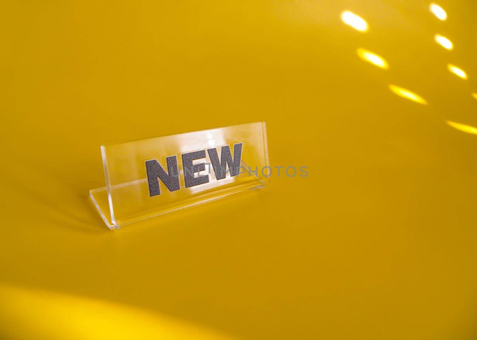 Transparent plastic price tag with black inscription new on a yellow background. Concept for sale or shop