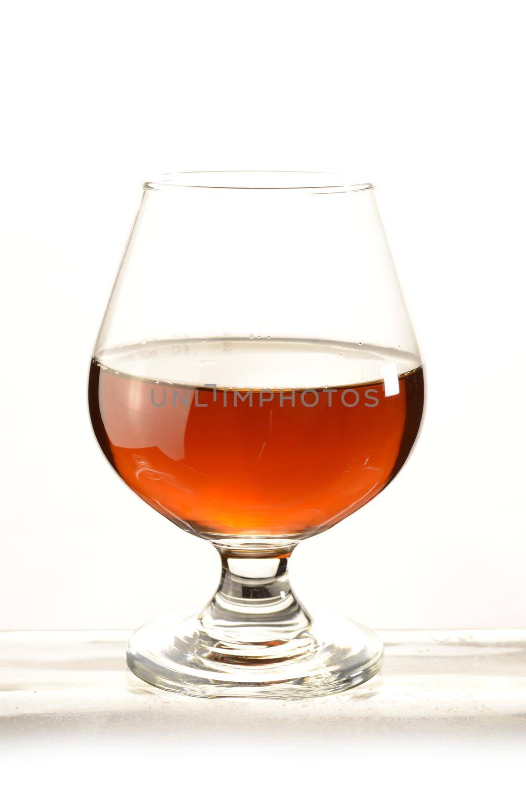 A glass of Cognac over a white background.